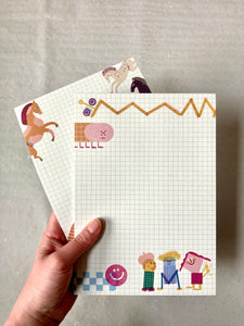 hand holding Friends Notepad with grid background and fun characters